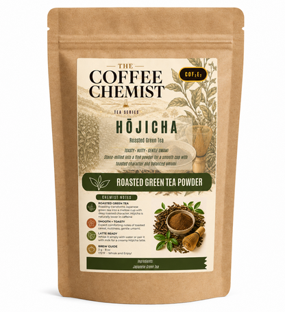 A stand-up kraft paper pouch of The Coffee Chemist Hōjicha Roasted Green Tea Powder, featuring a cream and green label with illustrations of tea plants and loose tea leaves.